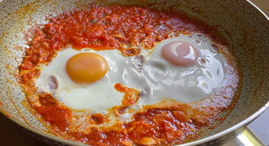 Uova in purgatorio, due uova cotte in una salsa rossa piccante, in una padella.