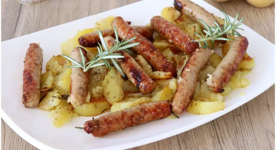 Salsiccia e patate al forno, un piatto rustico e saporito, con rosmarino fresco che profuma il tutto.