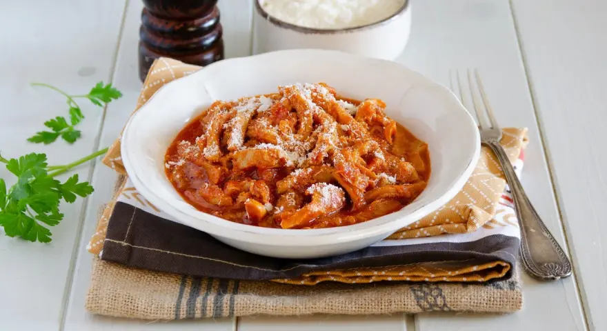 Un invitante piatto di trippa alla parmigiana, cosparso di formaggio grattugiato, pronto per essere gustato.