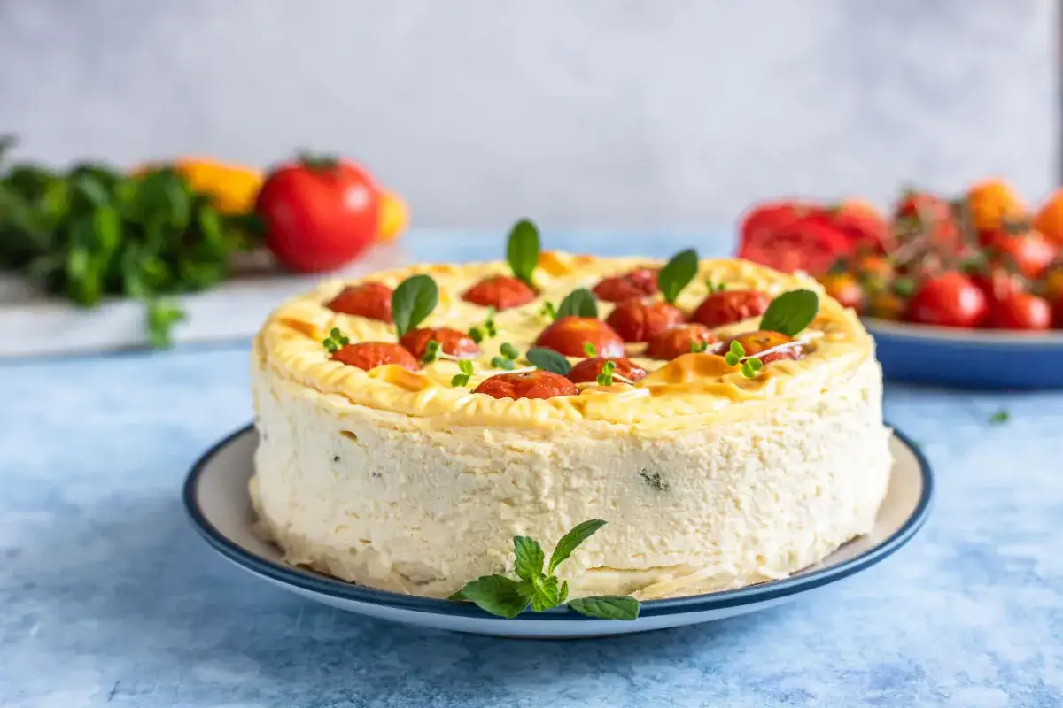 Cheesecake salata con taralli, decorata con pomodorini e basilico. Un'idea sfiziosa per un aperitivo o antipasto.