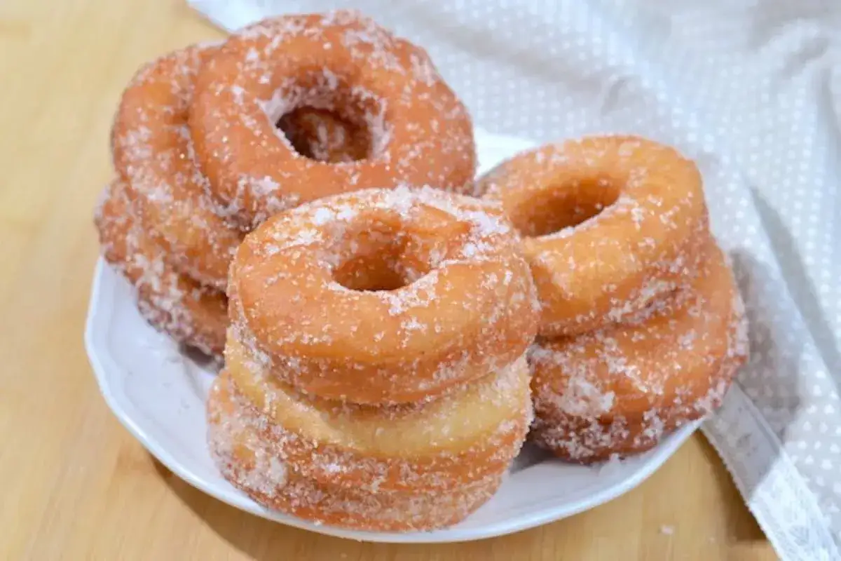Ciambelle fritte dorate e zuccherate, perfette per una ricetta golosa.