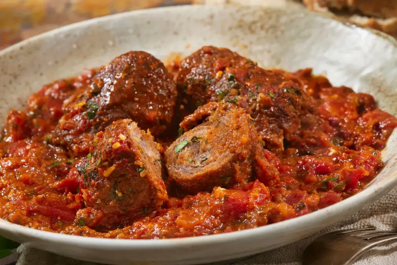 Involtini alla romana succulenti in salsa di pomodoro, un classico della cucina romana, serviti in una ciotola rustica.