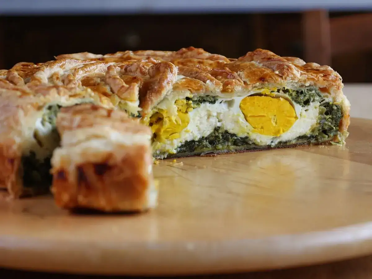 Torta Pasqualina originale genovese, fetta che rivela uova intere, ricotta e spinaci, racchiusi in una sfoglia dorata.