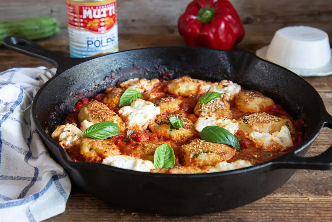 Polpette di pollo al sugo con ricotta e basilico, servite in padella. Ingredienti freschi e sapore autentico.