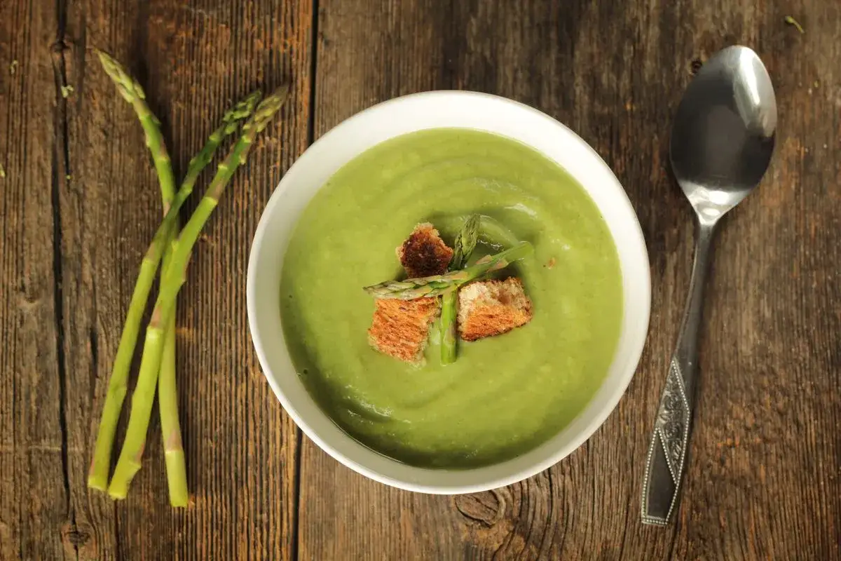 Zuppa cremosa, guarnita con crostini e asparagi freschi. Un delizioso pesto di asparagi pronto da gustare.