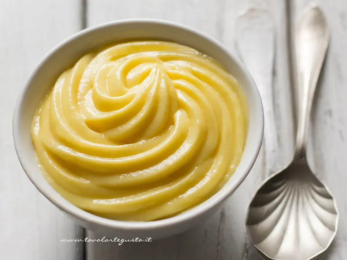 Una ciotola di deliziosa crema pasticcera veloce, con una cucchiaiata argentata accanto. Perfetta per ogni dolce!