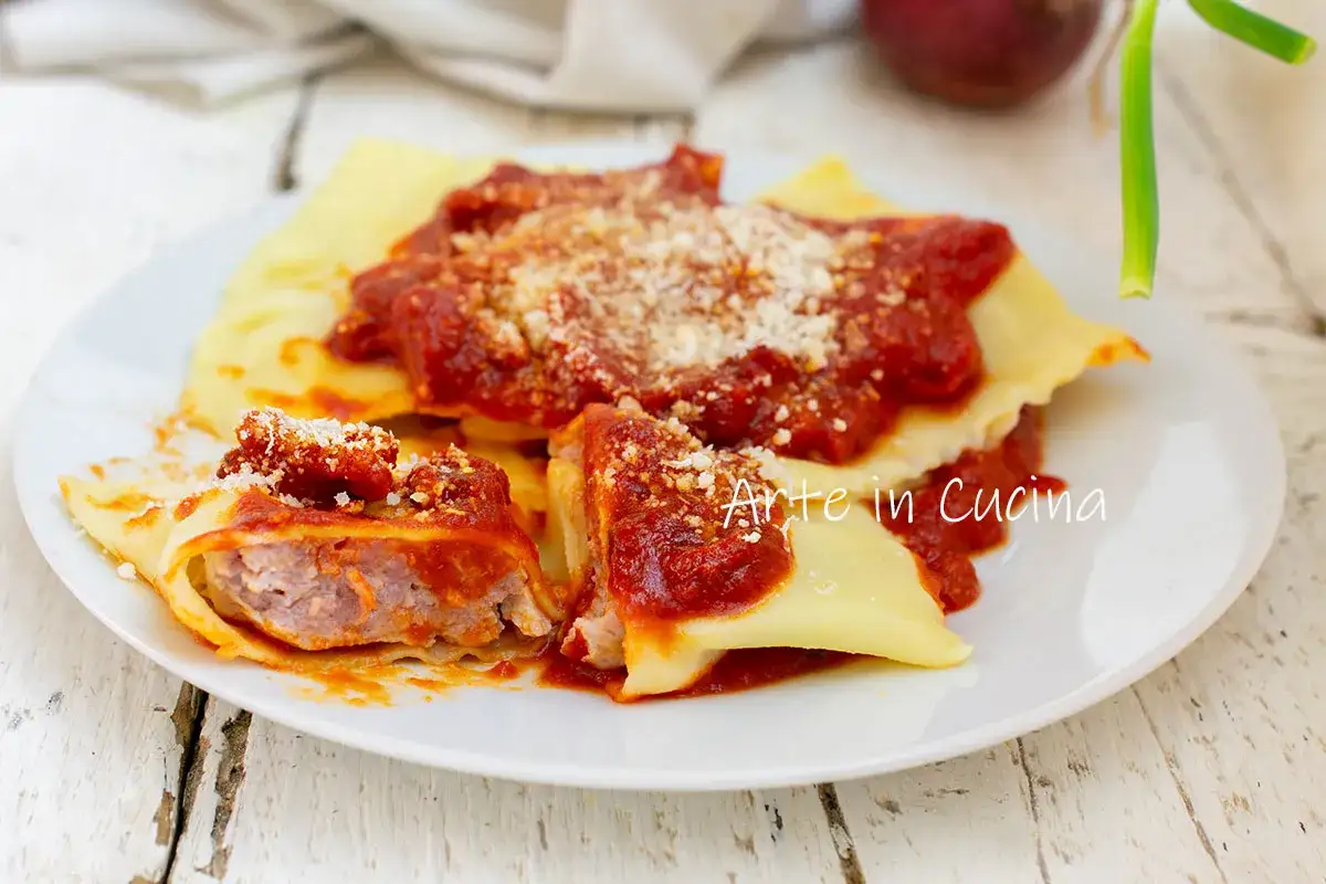 Ravioli fatti in casa con un saporito ripieno per ravioli, conditi con sugo rosso e parmigiano.