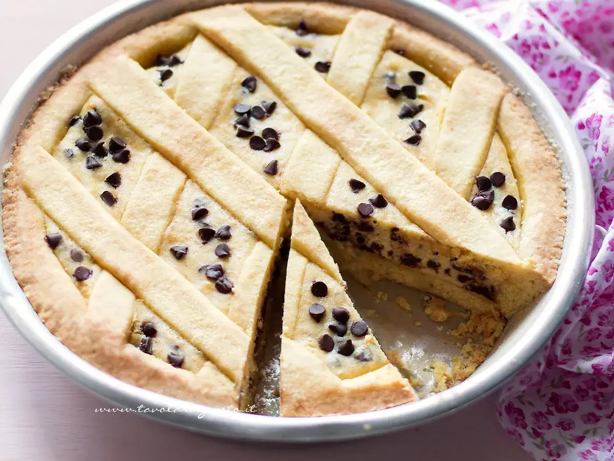 Deliziosa crostata ricotta e cioccolato con un reticolo di pasta frolla e gocce di cioccolato fondente.