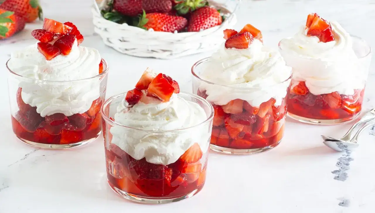 Deliziosi bicchierini di fragole con panna montata, guarniti con fragole fresche. Un dolce estivo perfetto.