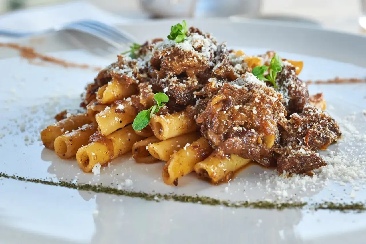 Ziti alla genovese, un piatto ricco e saporito con pasta e rag&ugrave; di carne, guarnito con parmigiano e erbe aromatiche.