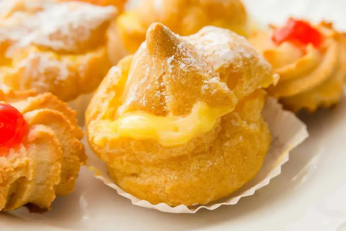Bign&egrave; alla crema soffici e dorati, spolverati di zucchero a velo, con un ripieno cremoso che cola.