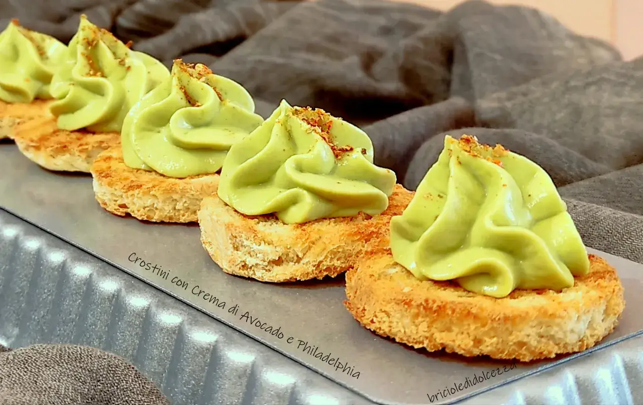 Crostini con soffice crema di avocado, guarniti con spezie. Un antipasto fresco e gustoso.