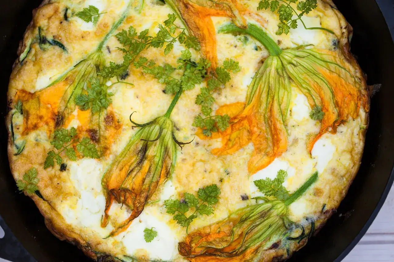 Frittata dorata con fiori di zucca e prezzemolo fresco, un piatto primaverile invitante.