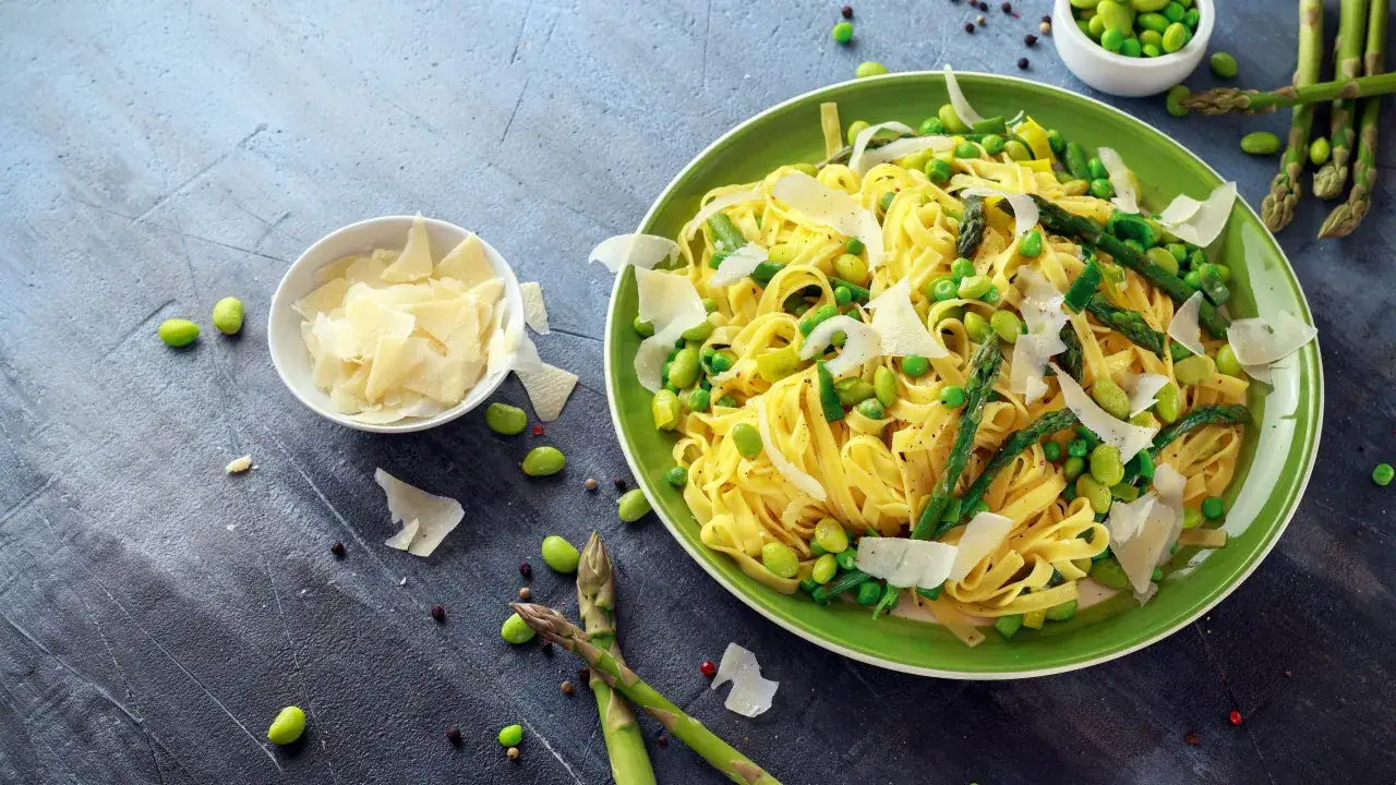 Un piatto di pasta fresca con asparagi selvatici, piselli e scaglie di parmigiano. Un'esplosione di sapori primaverili.