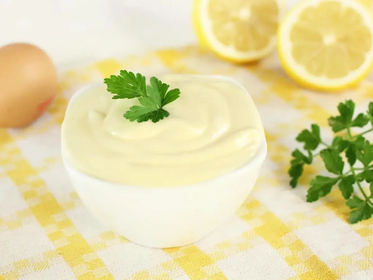 Una ciotola di cremosa maionese con uova sode, guarnita con prezzemolo fresco. Ingredienti per una maionese perfetta.