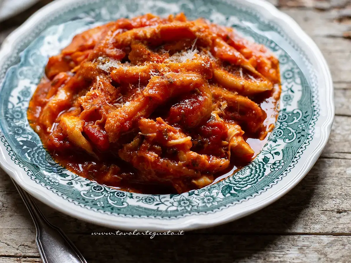 Trippa ricetta della nonna: un piatto fumante di trippa in umido con pomodoro e parmigiano, servito su un piatto decorato.