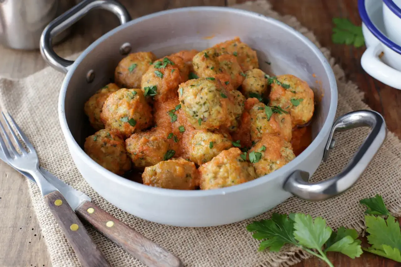 Deliziose polpette senza uova in salsa di pomodoro, guarnite con prezzemolo fresco. Un piatto gustoso e leggero.