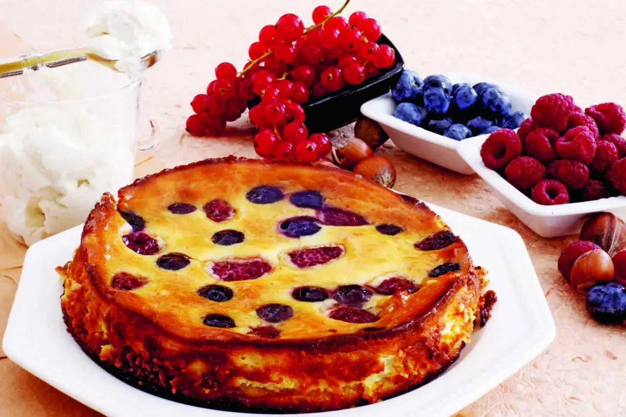 Cheesecake senza panna con frutti di bosco e ribes, accompagnata da una coppetta di panna montata.