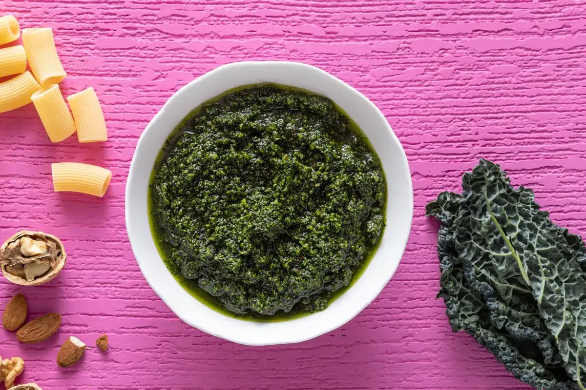 Pesto di cavolo nero pronto per condire la pasta, con ingredienti freschi come cavolo nero, noci e mandorle.