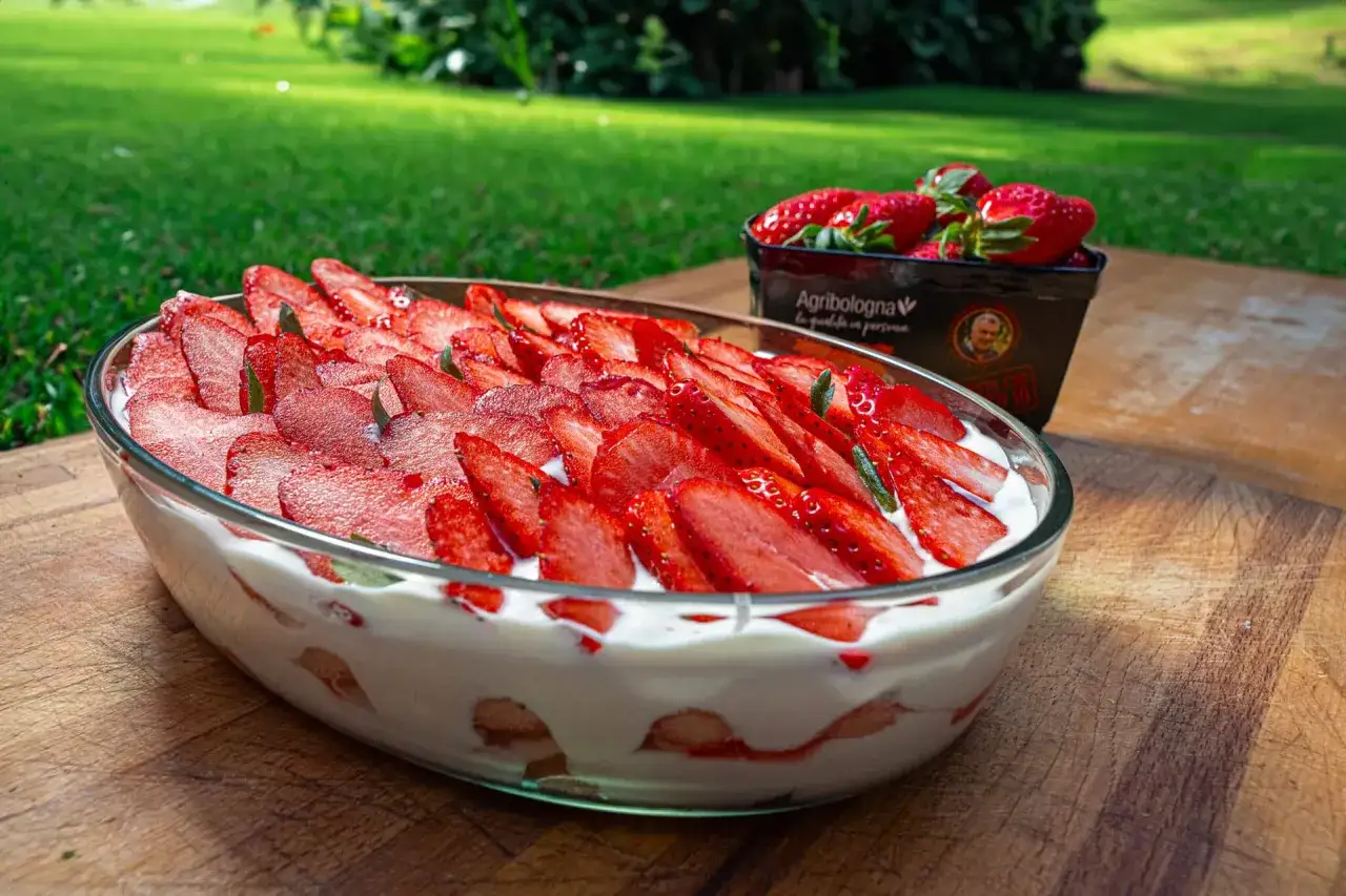 Un delizioso tiramisù alle fragole, con strati di crema e frutta fresca, pronto per essere gustato all'aperto.