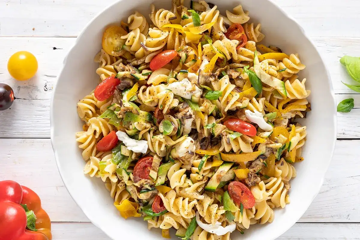 Un'insalata di pasta colorata con fusilli, pomodorini, zucchine, peperoni gialli e mozzarella fresca.