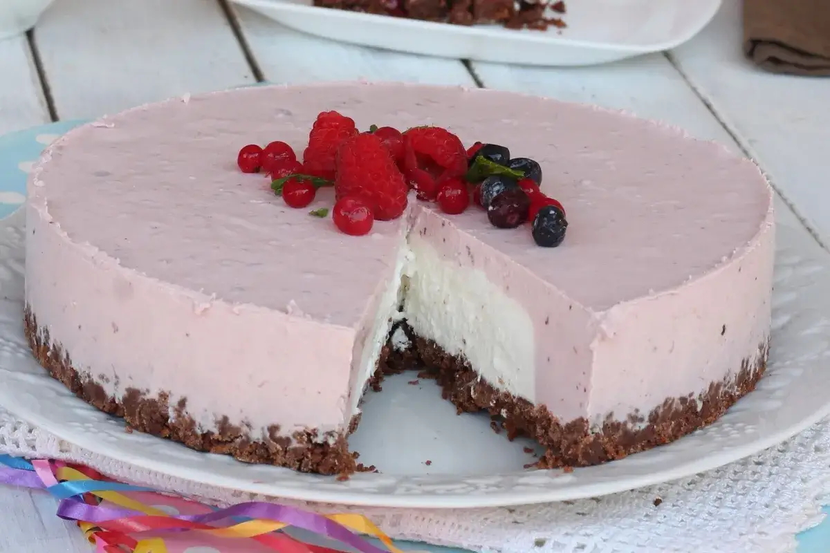 Deliziosa torta fredda allo yogurt con base croccante, guarnita con frutti di bosco freschi. Perfetta per un'occasione speciale.