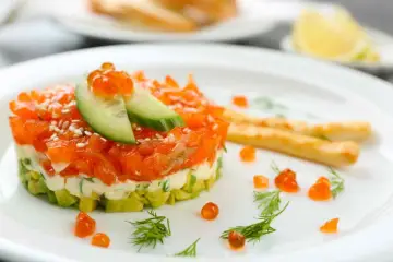 Tartare di salmone e avocado, un'idea per antipasti velocissimi senza cottura, guarnita con uova di pesce e cetriolo.