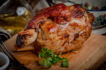 Stinco di maiale al forno, dorato e succulento, pronto per essere gustato. Un piatto che profuma di tradizione e sapore.