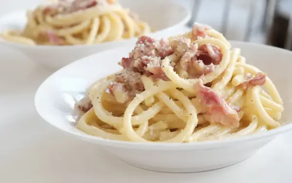 Un piatto di pasta alla gricia fumante, con guanciale croccante e pecorino romano grattugiato.