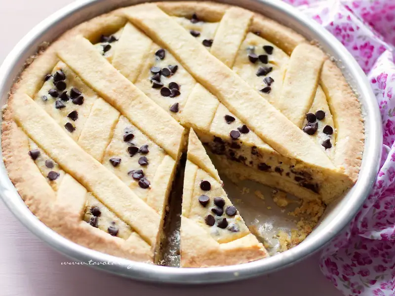 Deliziosa crostata ricotta e cioccolato con un reticolo di pasta frolla e gocce di cioccolato fondente.