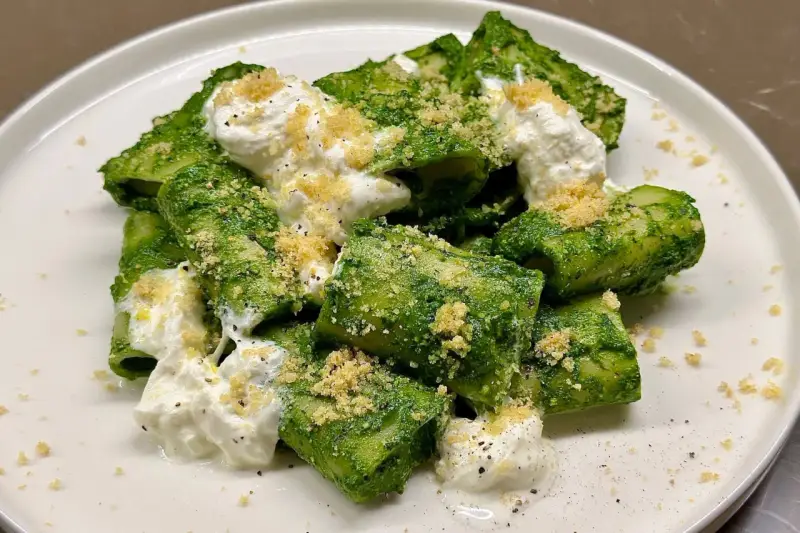 Paccheri conditi con un vibrante pesto di cavolo nero, arricchiti da ricotta fresca e pangrattato croccante.